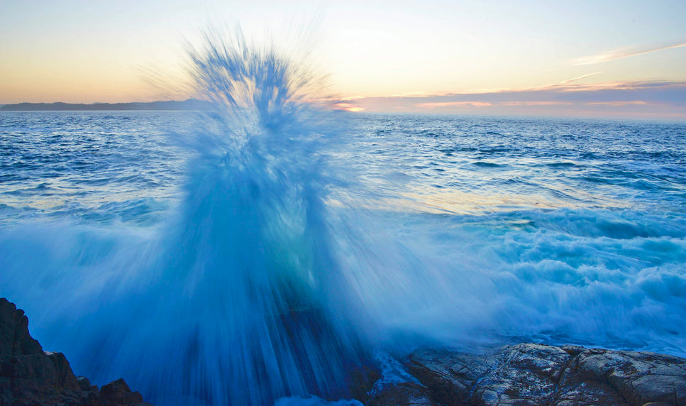 aqua colored wave slashes up to the sky at sunset