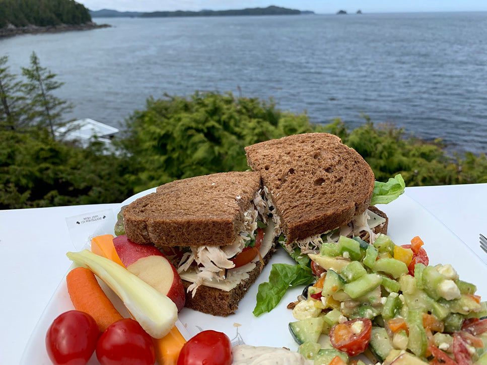 a meal of sandwich and famous malei island cob salad on outdoor patio